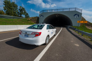 white car driving under arched tunnel