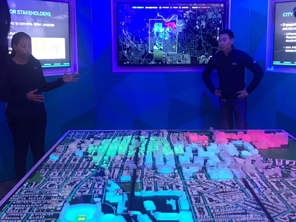 Ford City Insights meeting-display model of city with woman speaking