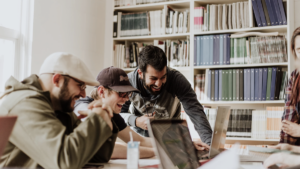 three individuals laughing at laptop