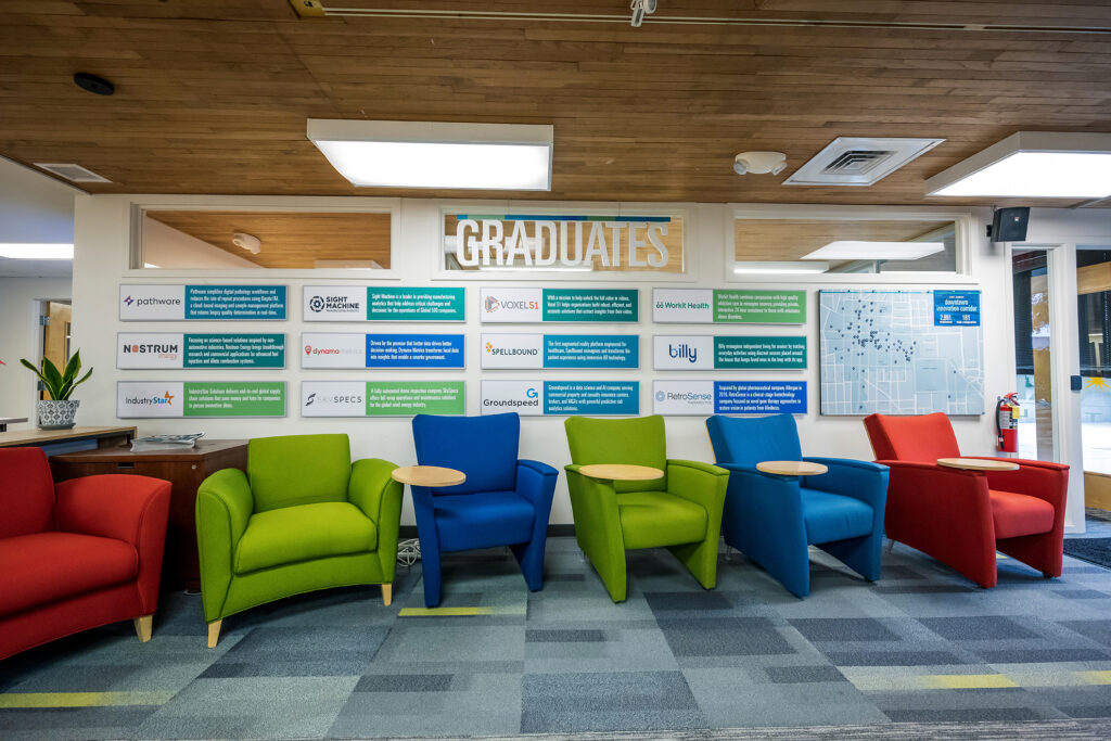 wall with company names and green, blue, and red chairs in front