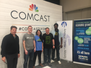 Krutko standing with 4 people in front of Comcast banner