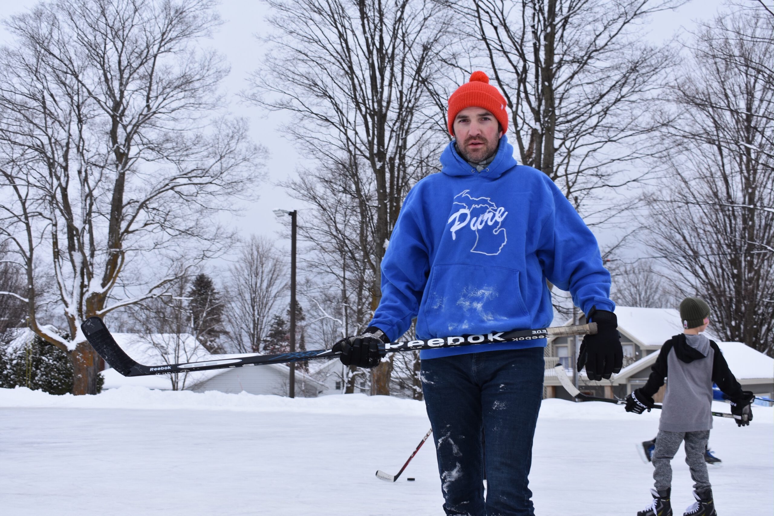 Scott Thomas playing hockey in Pure Michigan sweatshirt.