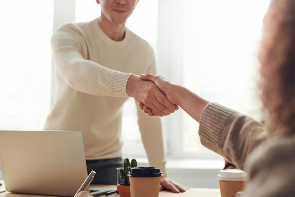 Two people shaking hands across a table.